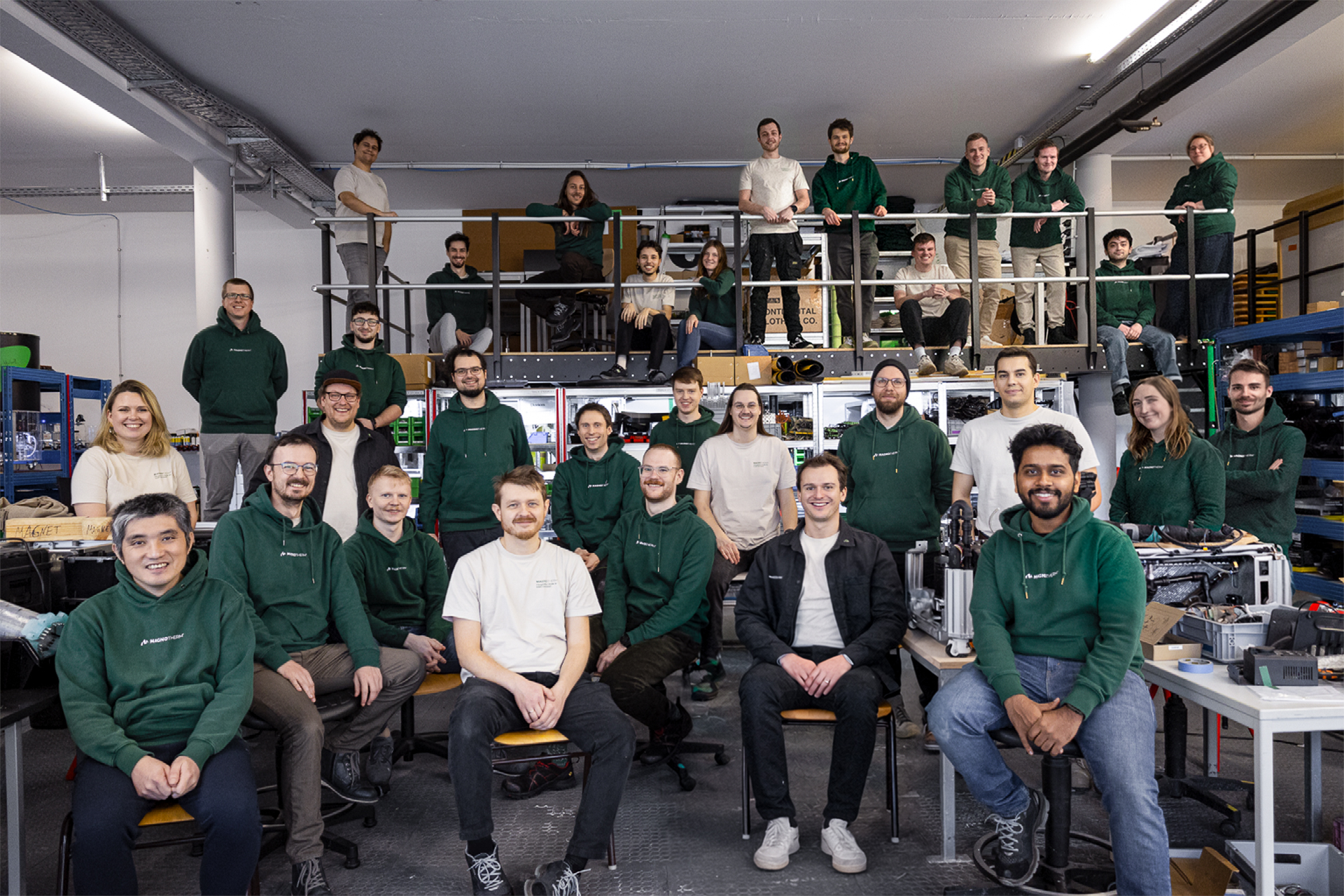 Group portrait of the roughly 30-person Magnotherm team in matching dark green company shirts, posed across two levels of their workshop in Darmstadt, Germany. Photo courtesy of Magnotherm.