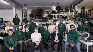 Group portrait of the roughly 30-person Magnotherm team in matching dark green company shirts, posed across two levels of their workshop in Darmstadt, Germany. Photo courtesy of Magnotherm.