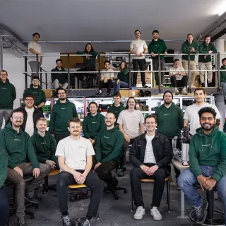 Group portrait of the roughly 30-person Magnotherm team in matching dark green company shirts, posed across two levels of their workshop in Darmstadt, Germany. Photo courtesy of Magnotherm.