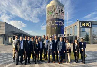 Group photo of the ReLiFe consortium members standing outside the Sunlight Group facility in Xanthi at the project's closing meeting, in front of a tall ReLiFe-branded display column under a blue sky