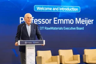 Professor Emmo Meijer standing behind a branded lectern in a navy blazer and light blue patterned shirt in front of a blue screen reading "Welcome and Introduction, Professor Emmo Meijer, Chair, EIT RawMaterials Executive Board."